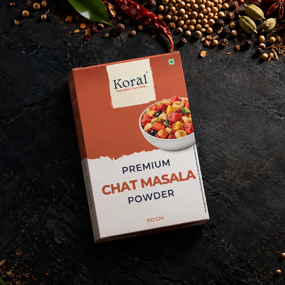 The Chat Masala Powder box lying on dark slate among whole spices