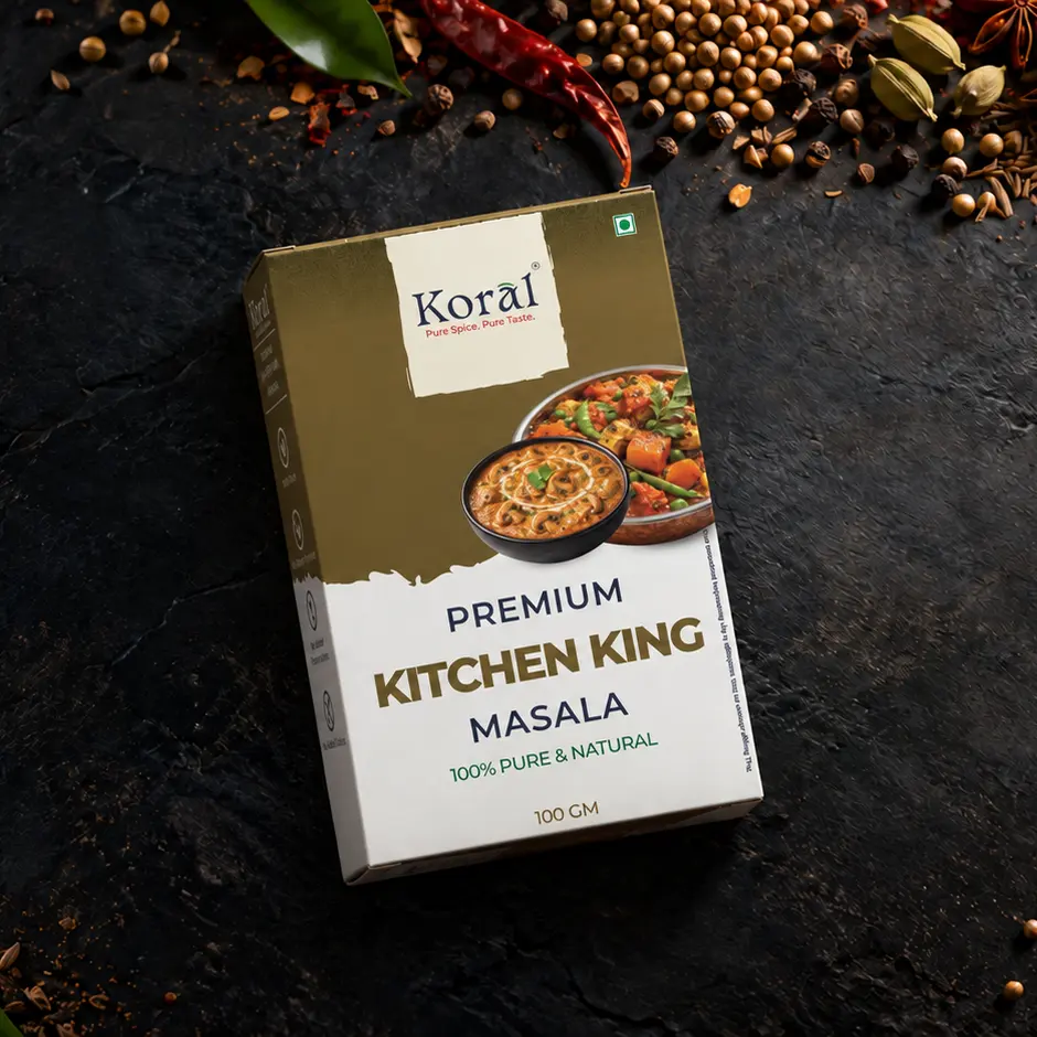 The Kitchen King Masala box lying on dark slate among whole spices
